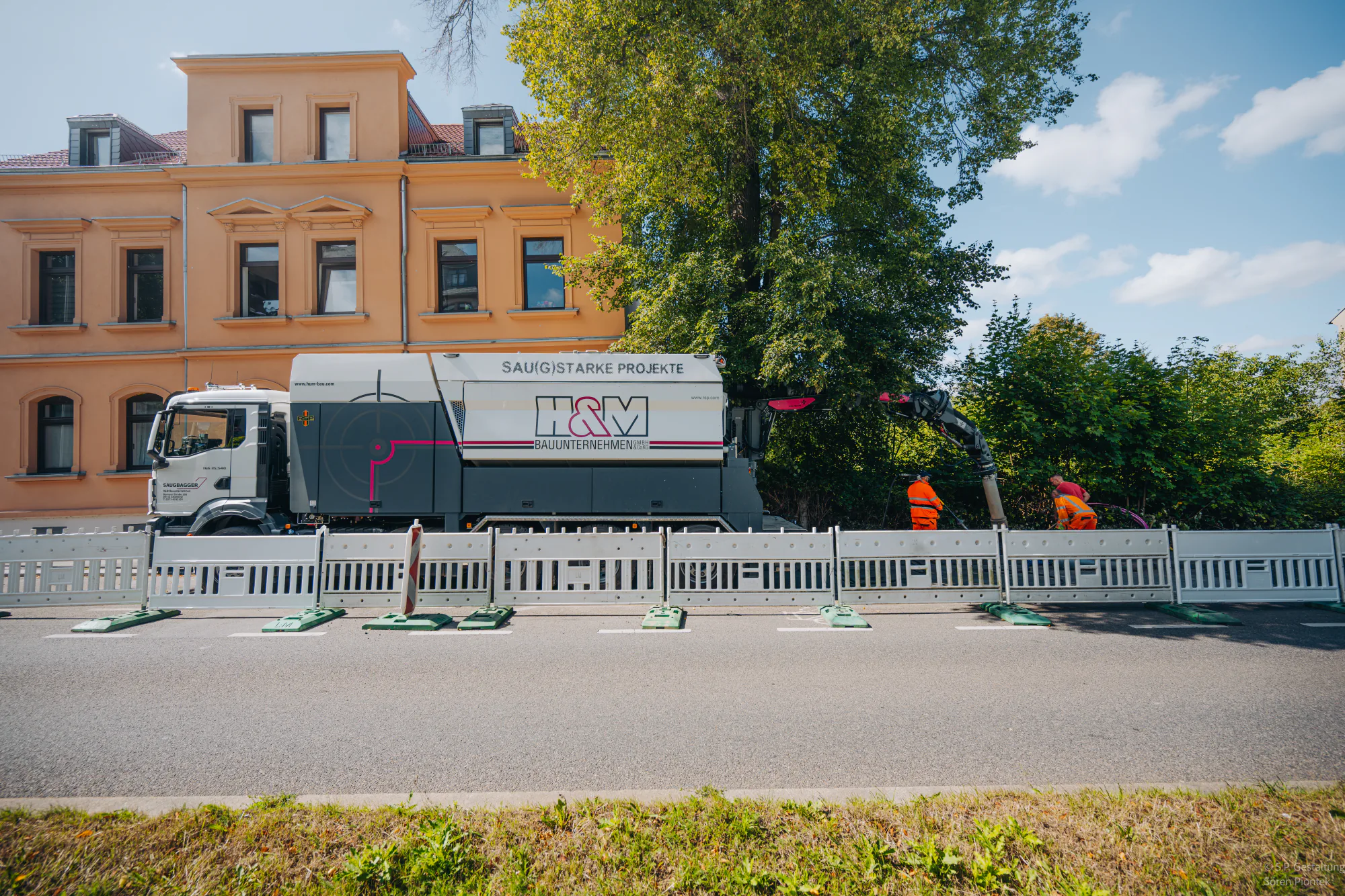 Firmeneigener Saugbagger auf einer abgesicherten Baustelle im Stadtgebiet